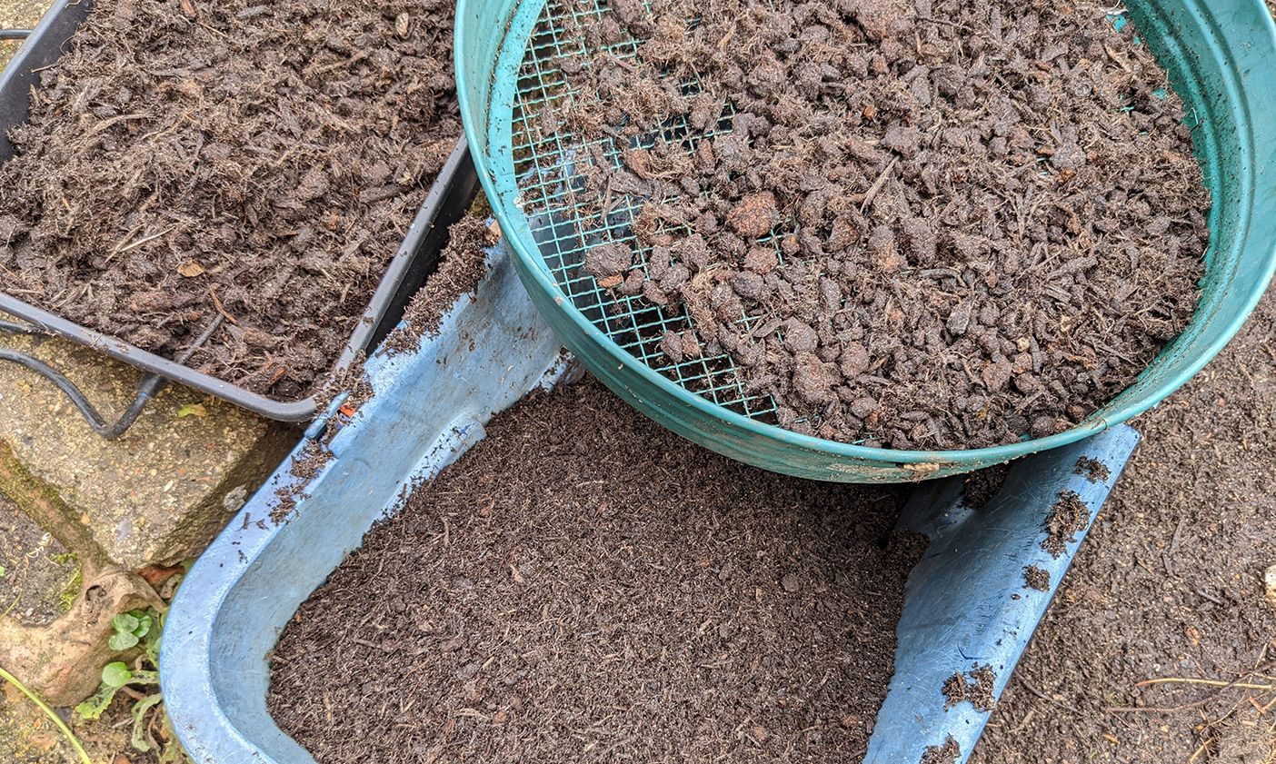 Compost lumps and bumps caught in the riddle and discarded into a tray for mulching